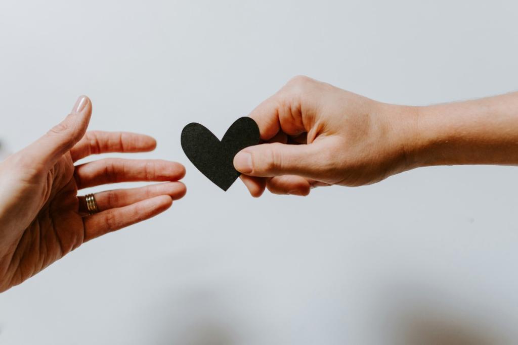 One hand giving a heart to another hand.